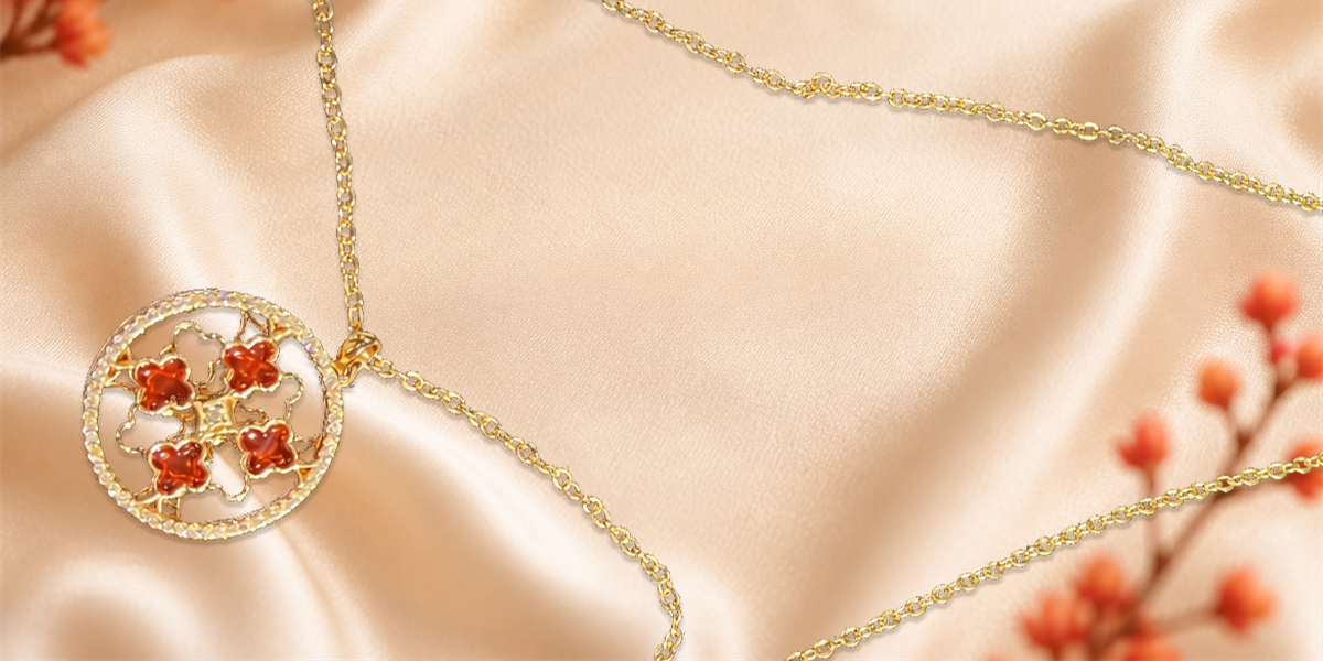 Gold vermeil floral pendant necklace photographed on champagne silk with red flowers